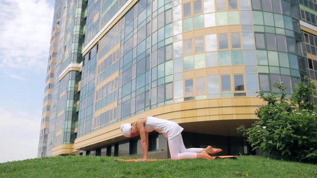 Master of Yoga Doing Asanas in the Park Near the House