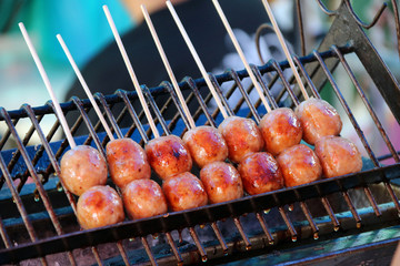 Thai sausage with wood stick grilling on the metal grill grate in the stove. Thai sausage is Local food of northeast of Thailand.