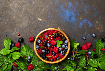 Summer berries in assortment with fresh berry and leaves, food background, top view