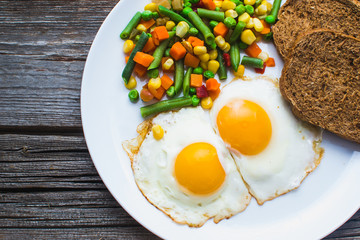 two fried eggs on the plate and vegetables