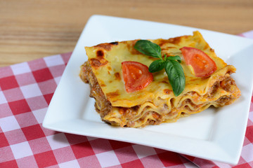 Tasty lasagna served on a wooden table. Italian food background. Closeup.