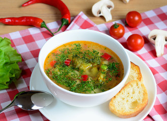 Vegetable minestrone soup with broccoli in a white bowl on a wooden background in a rustic style.