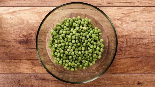 Peas slowly fill a rotating glass bowl - top view, timelapse