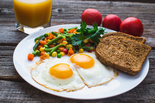 two fried eggs on the plate and vegetables
