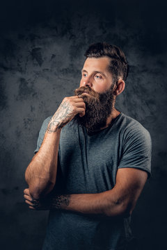 A man with tattooed arms over dark grey background.