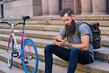 A man sits on a step and using a smartphone.