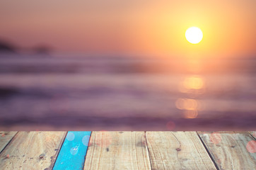 Blur beautiful tropical sunset beach with bokeh sun light wave on copy space empty old wood table...