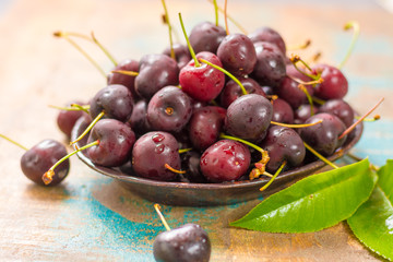 Fresh ripe black cherries in a bowl on a wooden background