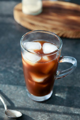 Glass cup with cold brew coffee and spoon on grey table
