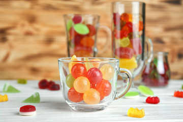 Colorful candies in glassware on wooden background