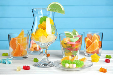 Colorful candies in glassware on wooden background