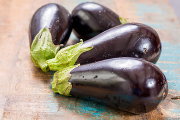 Ripe raw purple eggplants on a wooden background