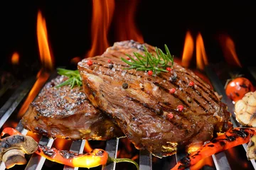 Papier Peint photo Lavable Steakhouse Grilled beef steak with vegetable on the flaming grill