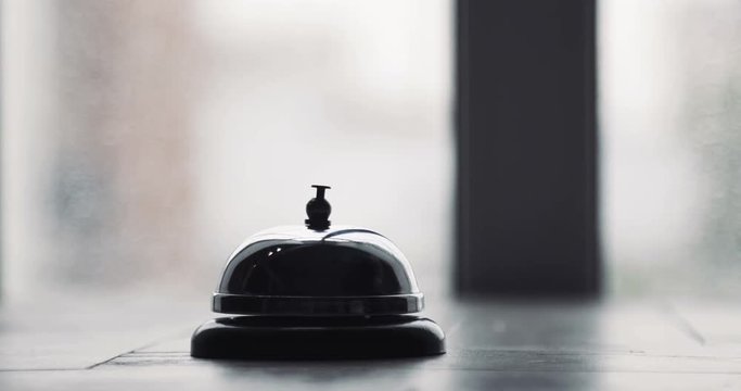 Man ringing hotel reception bell, male hand pushing accommodation call bell on wooden reception front desk