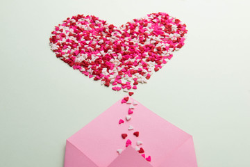 Sweets sugar candy hearts on envelope over green background