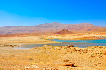 Fototapeta na wymiar panorama of the central, desert part of Morocco in bright sunny day, on the horizon a small mountain ridge, at her bottom the drying-up lake
