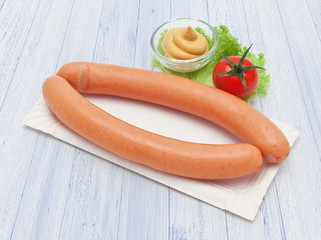 Ein Paar Wiener Würstchen mit Brötchen auf weißem Holzuntergrund