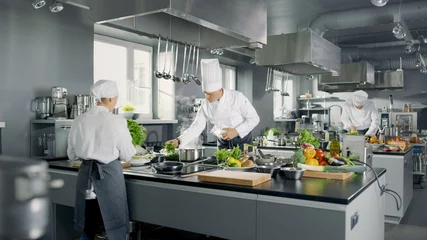 Fotobehang Groot en glamoureus restaurant Drukke keuken, chef-koks en koks die aan hun gerechten werken. © Gorodenkoff