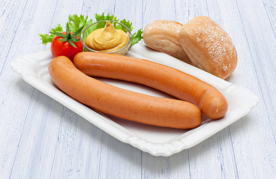 Ein Paar hei&szlig;e Wiener W&uuml;rstchen auf Pappdeckel und wei&szlig;em Holzuntergrund