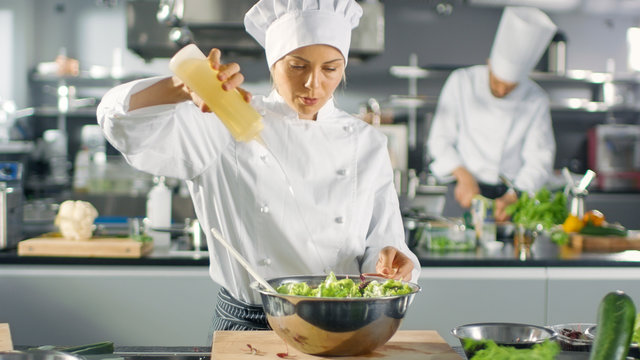 In a Famous Restaurant Female Cook Prepares Salad, ads Oil. She Works in a Big Modern Kitchen.