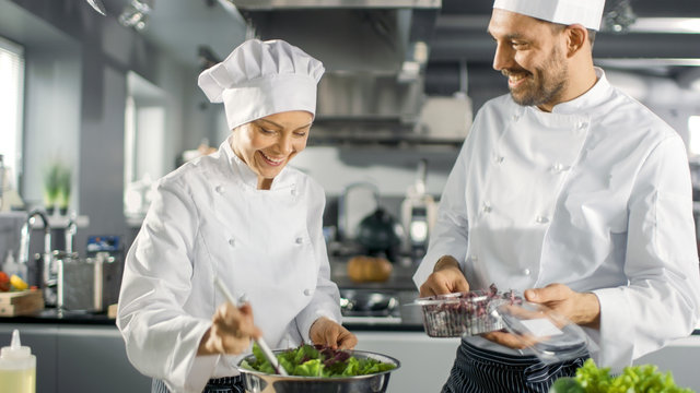 Male and Female Famous Chefs Team Prepare Salad for Their Five Star Restaurant. They Work on a Big Restaurant Stainless Steel Professional Kitchen.