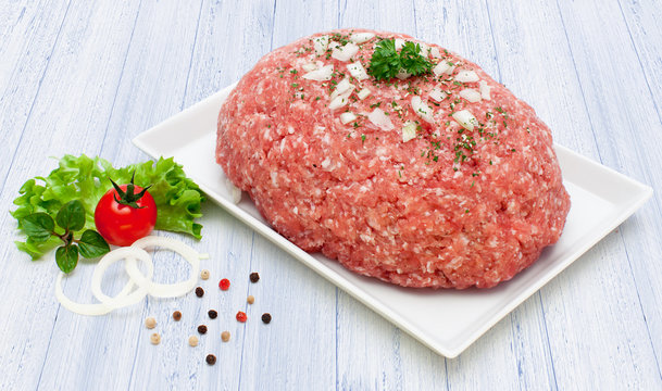 Frisches Schweinemett mit Zwiebeln auf wei&szlig;em Holzuntergrund