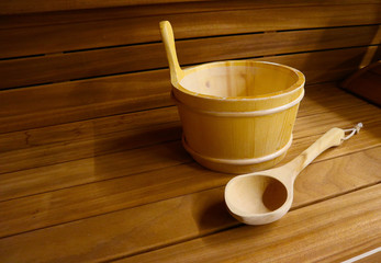 Wooden Bathhouse with scoop and tub tools close up. Wooden sauna interior with equipment.