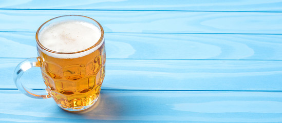 Mug of beer on an blue wooden table. Close up