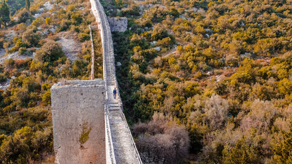 A man walking alone on the big wooden wall in Ston, Dalmatia, Croatia. Panoramic view of the wall of the ancient medieval fortress