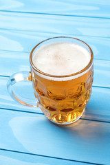 Mug of beer on an blue wooden table. Close up