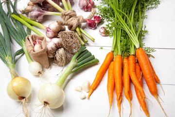 Fresh garlic, carrots and onions on a white background