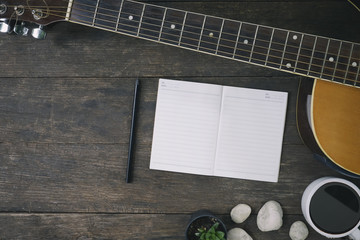 Desk of song composer for a work songwriter with a guitar and notepad on wood table.