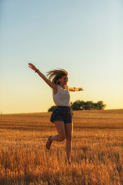 Woman jumping in the nature with arms wide open.