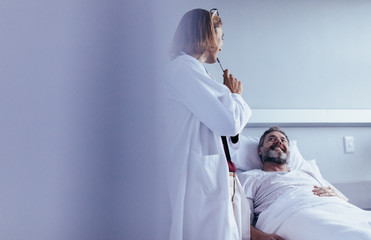 Doctor interacting with patient in hospital ward - obrazy, fototapety, plakaty