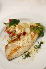 Hake fillet with grilled vegetables arranged on a plate, Traditional dish in elegant setting, Selective focus with soft light