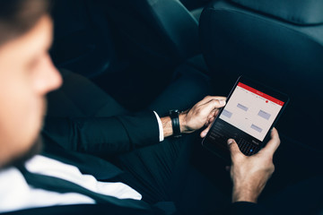 Businessman sitting in car scheduling meetings on smartphone