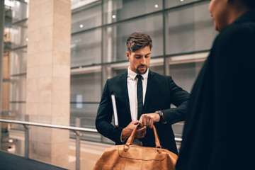 Businessman at airport with bag looking at his watch