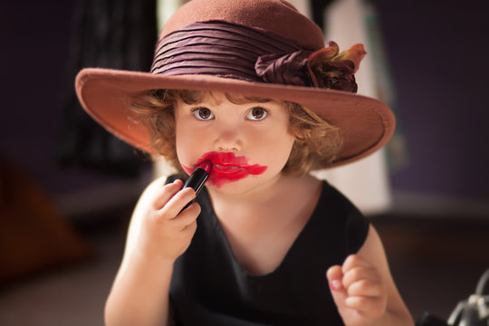 Little girl trying mom's lipstick. Growing up concept