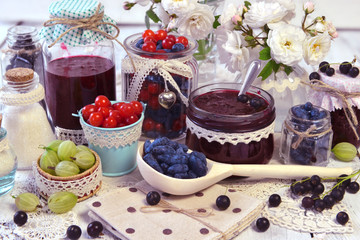 Spoon and vintage jars with homemade jam and fresh berry