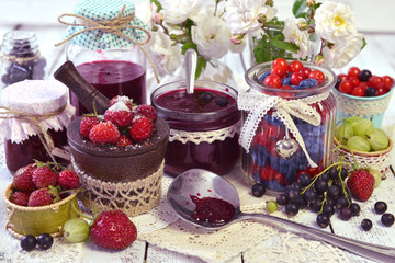 Fresh berry in assortment, spoon and vintage glass jars on the napkin