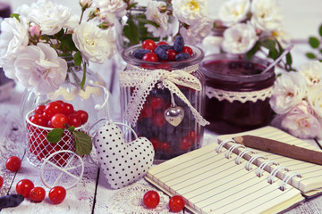 Obraz na płótnie Canvas Open notebook with copy space, vintage jars with fresh cherry and honey berry and homemade jam