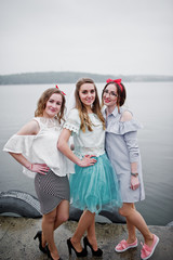 Fantastic bride with her two bridesmaids on the quay beside the lake at bachelorette party.