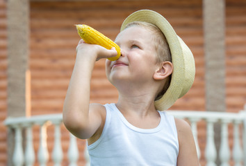 Boy in straw hat eat corn on the cob in the garden.Corn mood.