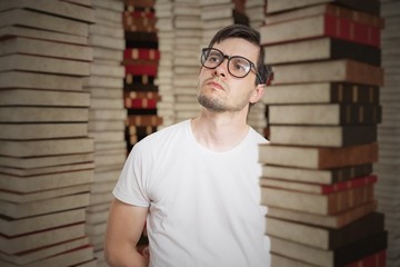 Fototapeta premium Young student in library and many stacked books.