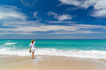 Young woman standing on a beach and enjoying the sun