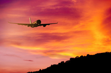 Fototapeta na wymiar Airplane flying over mountain and sunset sky background.