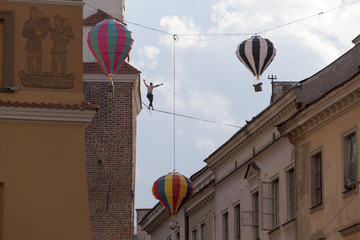 LUBLIN - JULY 28: Man practicing highline in Lublin during Urban High Line festiwal. Highline is a balance sport that consists walking through a rope clamped between two points and great height below. - obrazy, fototapety, plakaty