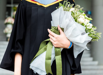 Graduated girl hold a bouquet of flowers.