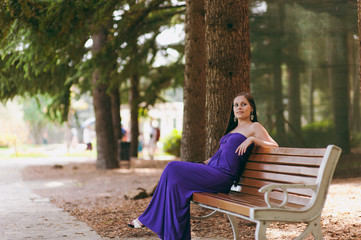Girl in a long purple dress walking in the park