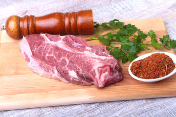 Raw beef steak with spices Leaves of coriander on wooden cutting board. Ready for cooking.